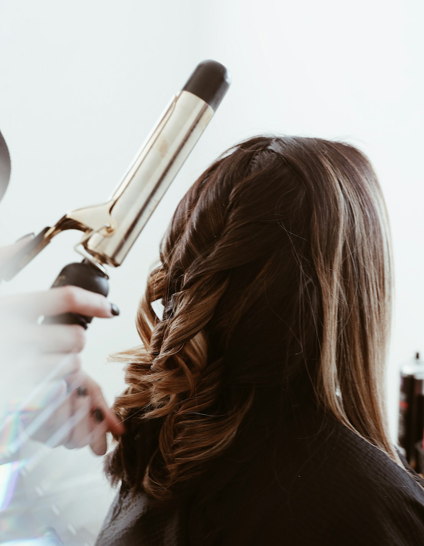A stylist sectioning a client's hair with a comb and shears.